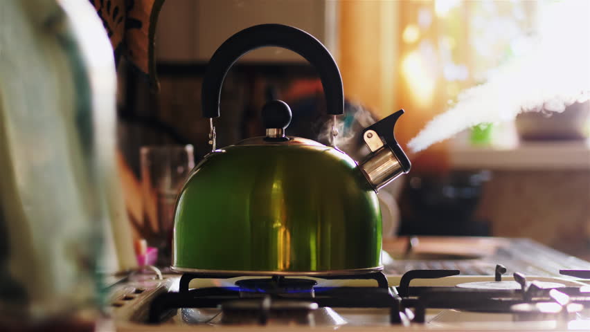 Boiling green kettle boiling with steam emitted from spout. The camera gently moves to the right. Solar glare from the kitchen window. Shallow depth of field Royalty-Free Stock Footage #1006807924