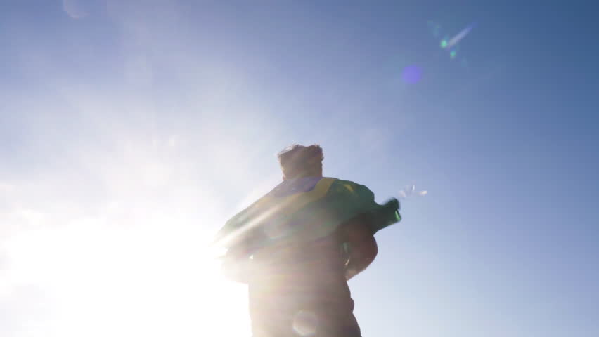 Young man holding brazilian national flag to the sky with two hands at the beach at sunset Royalty-Free Stock Footage #1006808626
