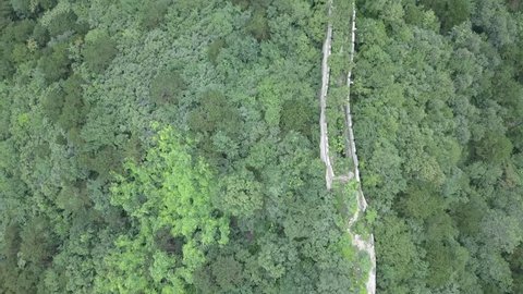 Aerial view of Mutianyu Great Wall while following its path with a drone tilting down trees nature 
