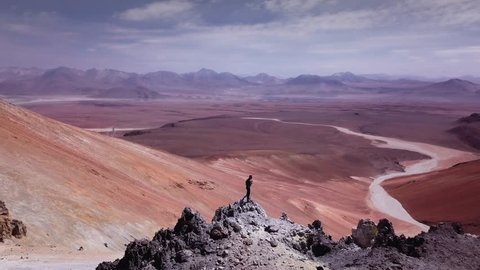 Male trail-runner on summit of the volcano Toco on Atacama desert, 4k. Aerial view of man contemplating the surroundings of volcano peak.