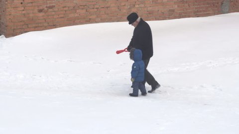CHAPAEVSK, SAMARA REGION, RUSSIA - JANUARY 24, 2018: Grandfather and his grandson walk in the snow