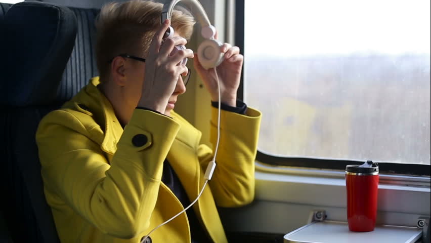 Pretty woman listening music in headphones on smartphone riding train, beautifull girl rides a city bus