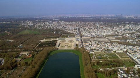 4K Aerial view above the palace of Versailles with landscaped gardens & the surrounding area