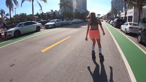 Trendy girl roller-skating on Miami South Beach road