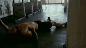 Muscular man tired after intense workout in cross fit gym. Exhausted man lying on gym floor after tough training session.
