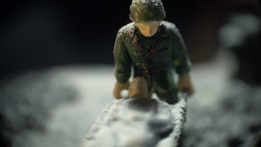 A toy soldier in military uniform carries a wounded man on a stretcher