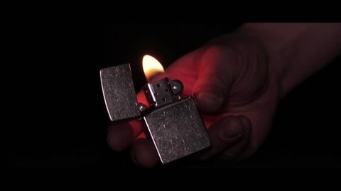close-up of the opening and the burning of iron Zippo lighter on a black background