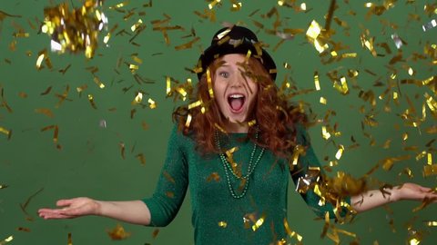 Young woman celebrating saint patrick's day on green wall moving in confetti