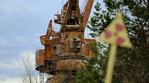 Sign of radiation hazard on the background of the crane. The Pripyat River. Chernobyl