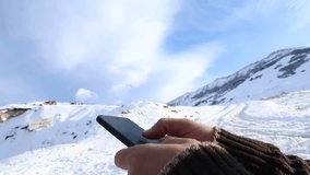 Man searching something on smartphone at mountain peak. Swiping with hand on cellphone.