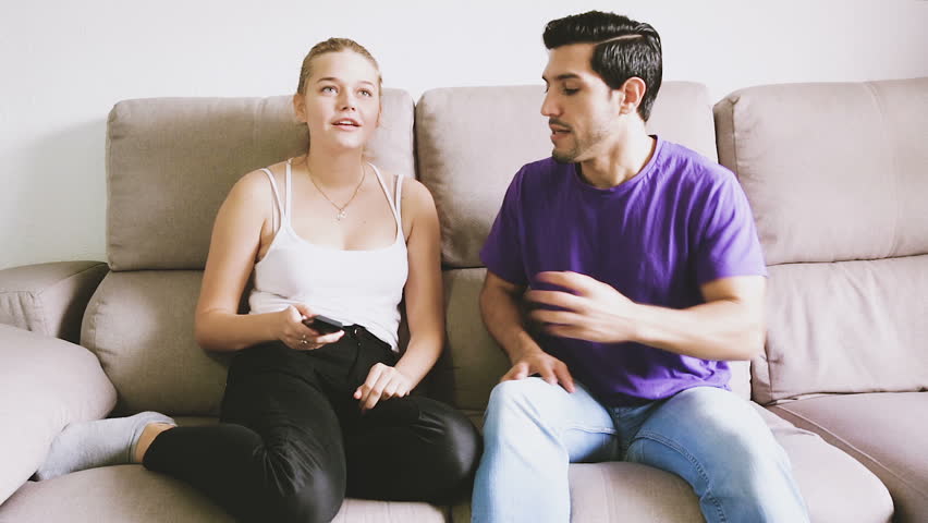 Young couple arguing because of TV remote control sitting on couch Royalty-Free Stock Footage #1006851481