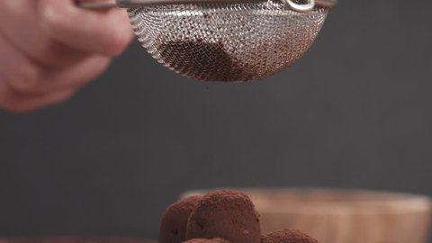 Slow motion sprinkling truffles with cocoa powder