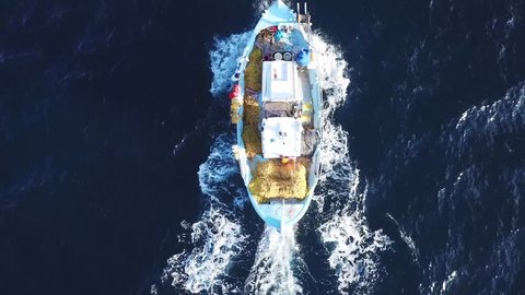 Aerial drone bird's eye view video of traditional fishing boat cruising in deep blue clear waters