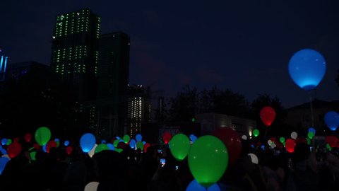 Concept of feast of love. Flying color helium glowing balloons balloons at night city sky.