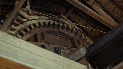 Close up of big old crafted wooden gear turning around being powered by the wind inside a Dutch windmill