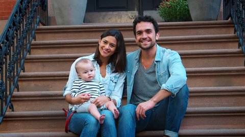 Young couple with a baby sitting on front stoop, close up