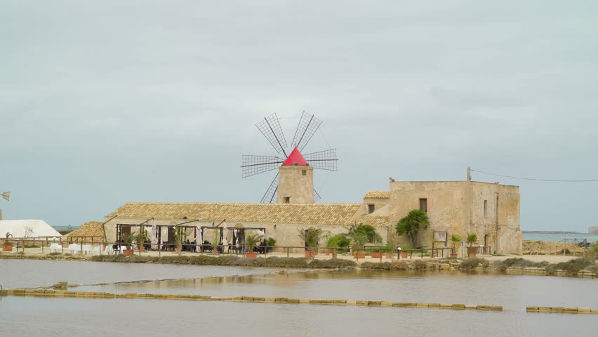 The tower with the windmill on the saltmine park in Trapani Sicily and the fields on the front in Italy