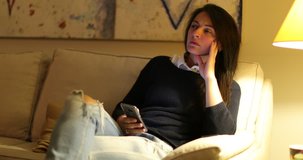 Woman checking her smartphone in candid authentic clip in living room sofa. Girl looking at cellphone device