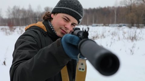 Young man aims gun for laser-tag game at winter day