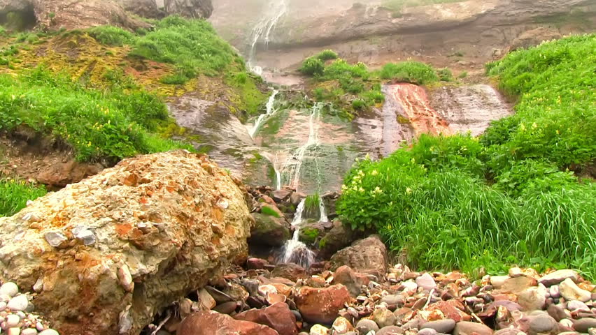Hot drops of water slowly fall in the stream of the geothermal river on the slope of the volcano. Kuril Islands, Itutrup Island, Baranskiy Volcano. Slowmotion 240 FPS