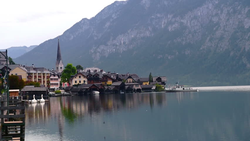 Early morning lake view with churches of Hallstatt in Austria alps with traditional buildings, mountains and boats on the lake Hallstatt village early morning lake view with church.