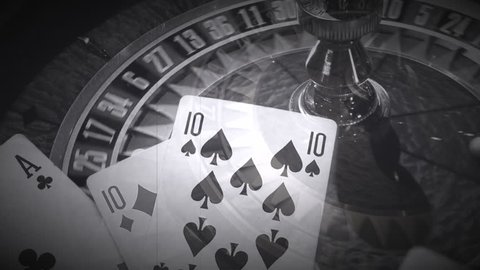 Close up of spinning roulette wheel in casino with superimposition of rolling dice and playing cards playing hands made like an old movie film in black and white