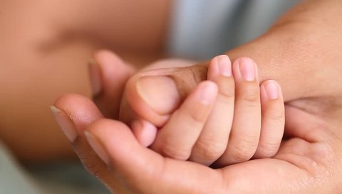 Cute newborn baby boy holding mother's finger