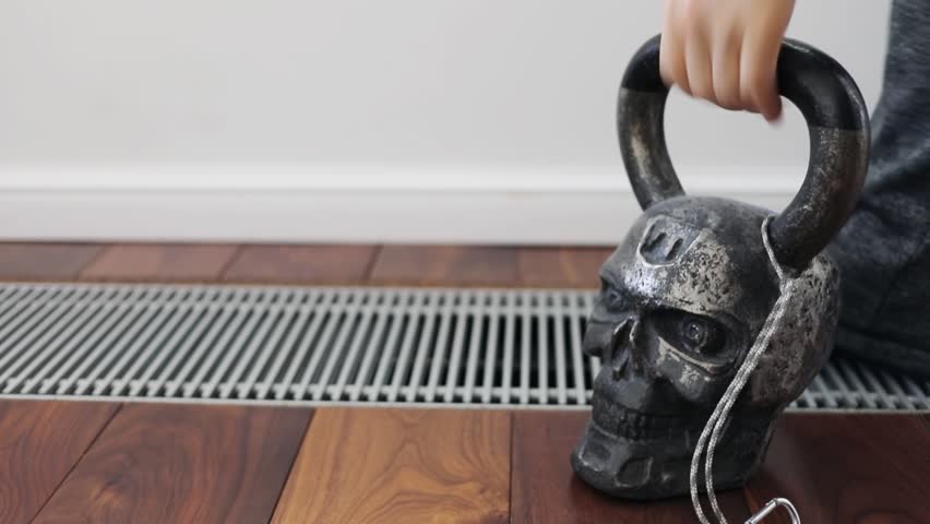 Hand take kettlebell in form of skull from floor and put it back.