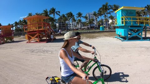 Couple of tourists riding bike in Miami beach