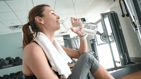 Fitness girl relaxing on sports bench and drinking water
