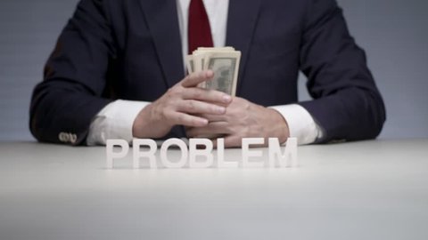 Word problem composition from white letters standing on background man in business suit holding bundle of money in hands. Business man holding in hands cash bundle