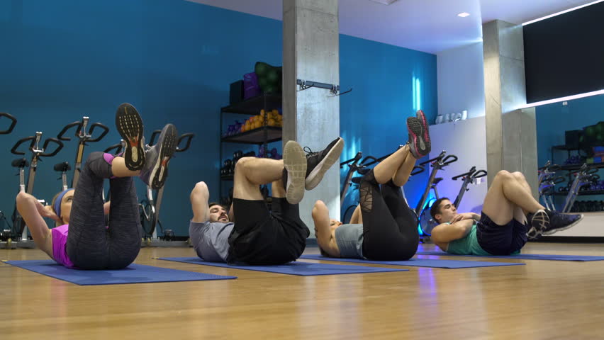 Four people doing crunches in a gym