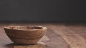 Slow motion pine nuts falling into wood bowl with copy space
