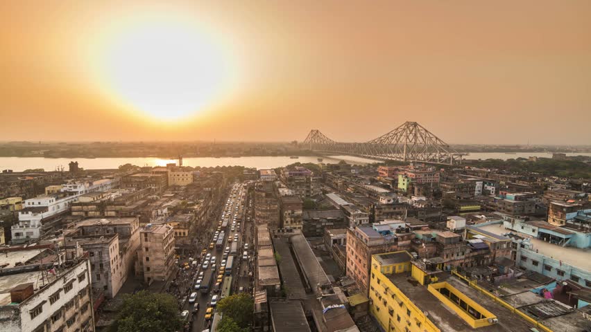 4K Timelapse of a beautiful sunset over Kolkata city with a Howrah bridge on the Ganga river, West Bengal, India.