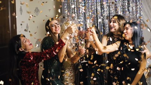 Young woman in glitter dress cheers and drink champagne in flying confetti on New Year party. Super slow motion. 