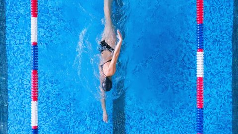 A woman swims in crawl in an open back swimsuit. 