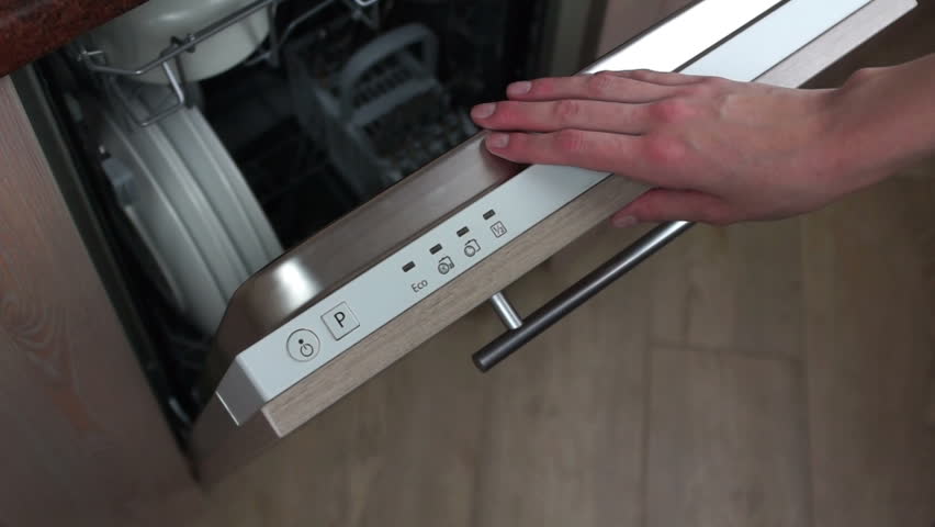 The girl chooses the dishwashing program on the dishwasher built into the kitchen and then closes the dishwasher cover | Shutterstock HD Video #1006956820