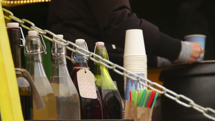 Seller pouring hot mulled wine to customers at roadside cafe, small business