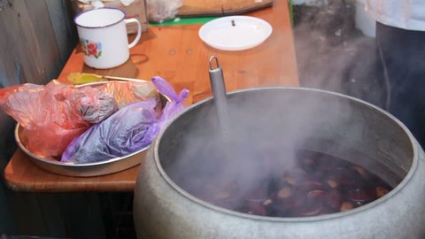 Beverage brewing in huge cauldron in yard to warm poor people, charity kitchen
