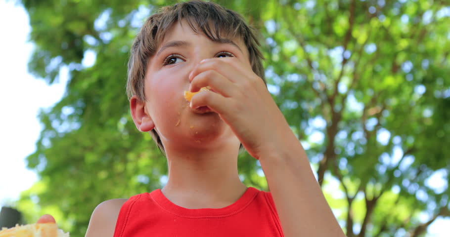 Child enjoying an orange outdoors in the sunlight. Young boy eating healthy fruit in 4K | Shutterstock HD Video #1006965466