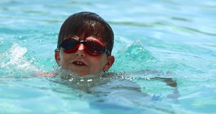 Young boy holding himself into the poolside in 4k clip resolution. Child enjoying summer vacations by holding himself to the safety spot of the swimming pool