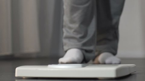 Playful overweight man stepping on scales and raising his foot, weight loss
