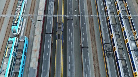 Aerial top down view of railway hub and parked passenger trains next to each other moving slowly over the rail vehicles with different colors beautiful rail network scene 4k high resolution footage