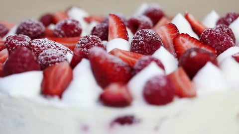 Strawberry, raspberry in powdered sugar and whipped cream turn, close-up