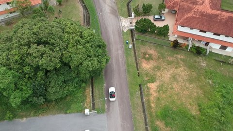 Aerial video following a car cruising in a neighborhood