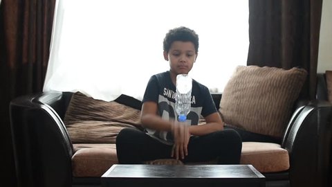Cute mixed boy doing bottle flip challenge at home and after making dab. Children have a fun. African american kids bottle fun. 