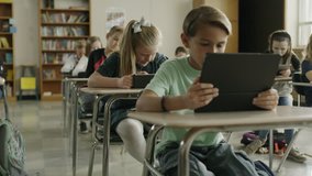 Panning shot of children in classroom reading digital tablets / Provo, Utah, United States
