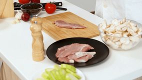 Cook salting a piece of raw pork meat on wooden board on the table