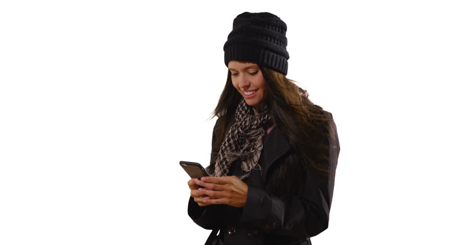 Caucasian female wearing a coat and scarf texting in studio with copyspace. Portrait of millennial woman using mobile phone on white background. 4k