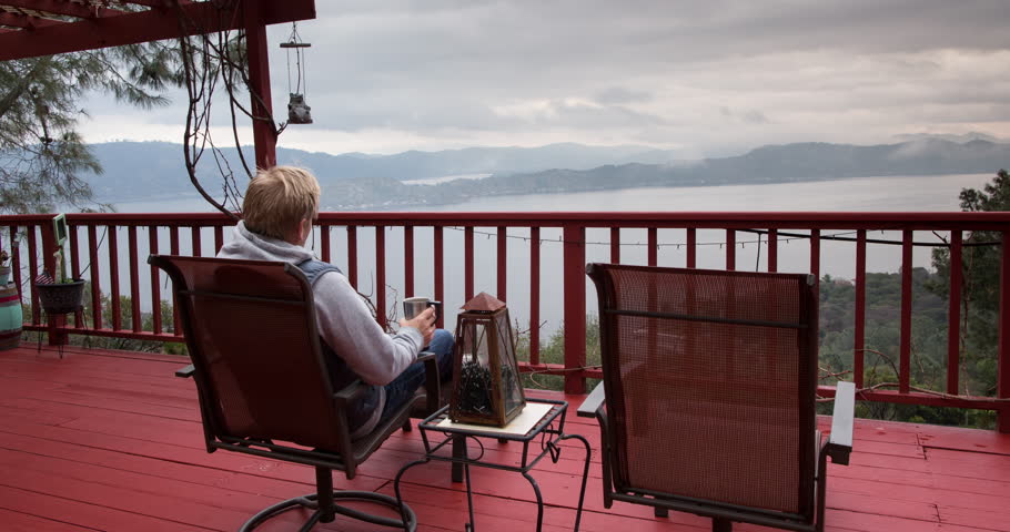 Man Drinking Coffee in a chair with Panoramic Landscape view of mist and fog. 